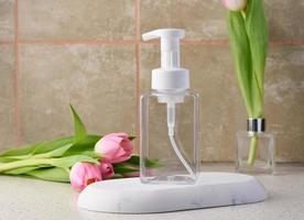 Transparent plastic container with a dispenser on the table. Bottle for liquid soap, shampoo photo