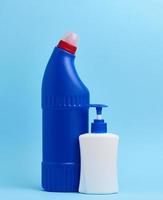 White plastic bottle with dispenser and blue plastic bottle for chemical detergents on a blue background photo
