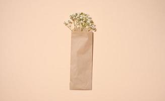 ramo de flores de blanco Gypsophila en un marrón Kraft papel bolso en un beige fondo, parte superior ver foto