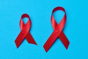 un seda rojo cinta en el formar de un arco en un azul fondo, un símbolo de el lucha en contra SIDA y un firmar de solidaridad y apoyo foto