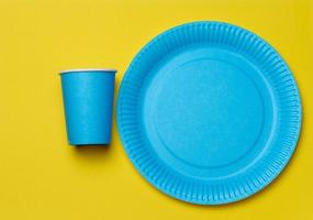 Round disposable blue paper plates and cups for a picnic, recyclable waste, top view. photo