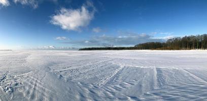 winter panorama, frozen endless expanse of the lake, white snow with traces, blue sky, clear frosty air, sunny day photo