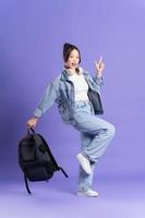 retrato de un hermosa asiático Chica de escuela vistiendo un mochila en un púrpura antecedentes foto