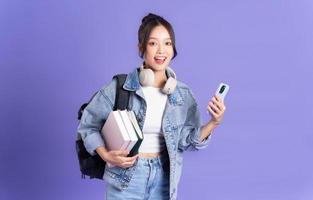 retrato de un hermosa asiático Chica de escuela vistiendo un mochila en un púrpura antecedentes foto