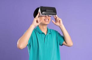 image of asian man wearing virtual reality glasses on purple background photo