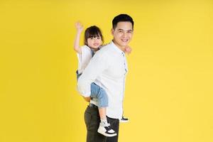 image of two happy father and daughter playing, isolated on yellow background photo