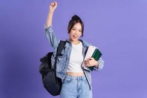 retrato de un hermosa asiático Chica de escuela vistiendo un mochila en un púrpura antecedentes foto