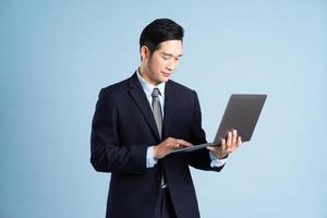 portrait of asian businessman wearing suit on blue background photo