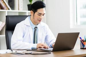 Asian male doctor portrait sitting at work photo