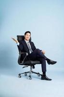 asiático empresario masculino retrato sentado en silla y aislado en azul antecedentes foto