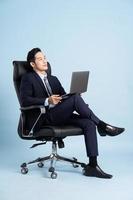 Asian businessman male portrait sitting on chair and isolated on blue background photo