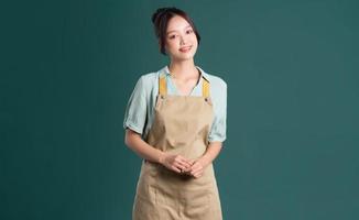portrait of Asian woman wearing apron on green background photo