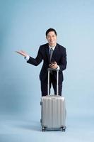 retrato de asiático empresario vistiendo un traje y tracción un maleta foto