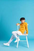 Portrait of sitting boy, isolated on blue background photo