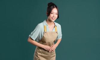 portrait of Asian woman wearing apron on green background photo