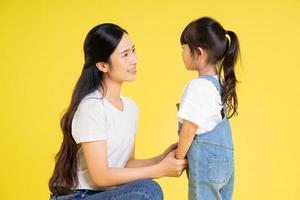 image of asian mother and daughter posing on a yellow background photo