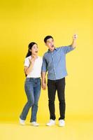 full body image of asian couple posing on yellow background photo