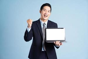 portrait of asian businessman wearing suit on blue background photo