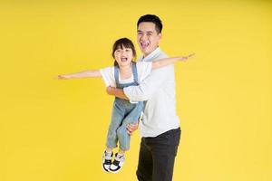 image of two happy father and daughter playing, isolated on yellow background photo