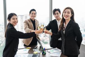 group of Asian business people holding glasses of wine to celebrate new year photo