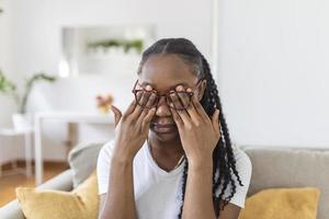 African girl in glasses rubs her eyes, suffering from tired eyes, ocular diseases concept photo