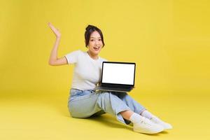 portrait of a beautiful young asian girl sitting on a yellow background photo