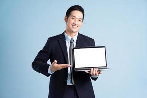 portrait of asian businessman wearing suit on blue background photo