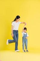 image of asian mother and daughter posing on a yellow background photo