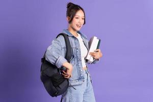 retrato de un hermosa asiático Chica de escuela vistiendo un mochila en un púrpura antecedentes foto