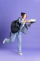 retrato de un hermosa asiático Chica de escuela vistiendo un mochila en un púrpura antecedentes foto