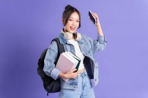 retrato de un hermosa asiático Chica de escuela vistiendo un mochila en un púrpura antecedentes foto