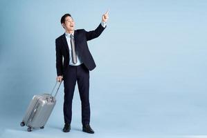 Portrait of Asian businessman wearing a suit and pulling a suitcase photo