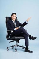 Asian businessman male portrait sitting on chair and isolated on blue background photo