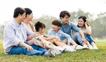 imagen de un asiático familia sentado juntos en el césped a el parque foto