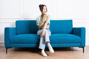 image of young Asian girl sitting on sofa at home photo