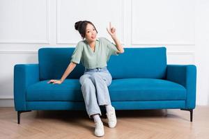 image of young Asian girl sitting on sofa at home photo