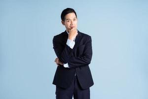 portrait of asian businessman wearing suit on blue background photo