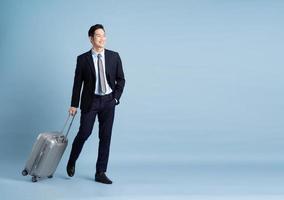 Portrait of Asian businessman wearing a suit and pulling a suitcase photo