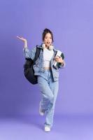 retrato de un hermosa asiático Chica de escuela vistiendo un mochila en un púrpura antecedentes foto