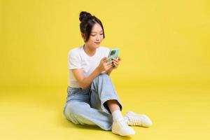 portrait of a beautiful young asian girl sitting on a yellow background photo