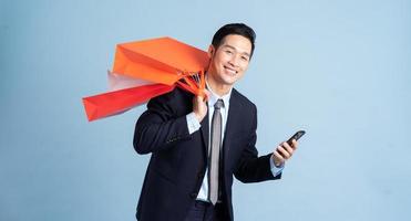 Asian businessman male portrait holding shopping bag on blue background photo