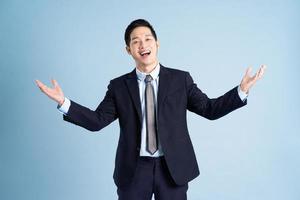 portrait of asian businessman wearing suit on blue background photo