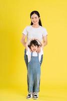 image of asian mother and daughter posing on a yellow background photo