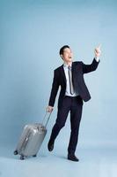 Portrait of Asian businessman wearing a suit and pulling a suitcase photo