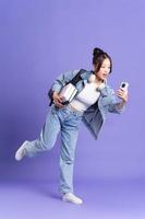 Portrait of a beautiful Asian schoolgirl wearing a backpack on a purple background photo