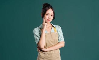 portrait of Asian woman wearing apron on green background photo
