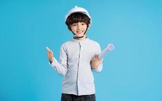 Asian boy portrait playing the role of an engineer, isolated on blue background photo