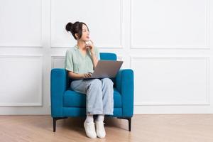 image of young Asian girl sitting on sofa at home photo