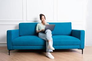image of young Asian girl sitting on sofa at home photo