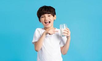 Portrait of asian boy holding cup of milk, isolated on blue background photo